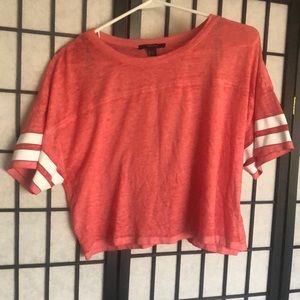 A pink cropped top with white stripes on the sleeves